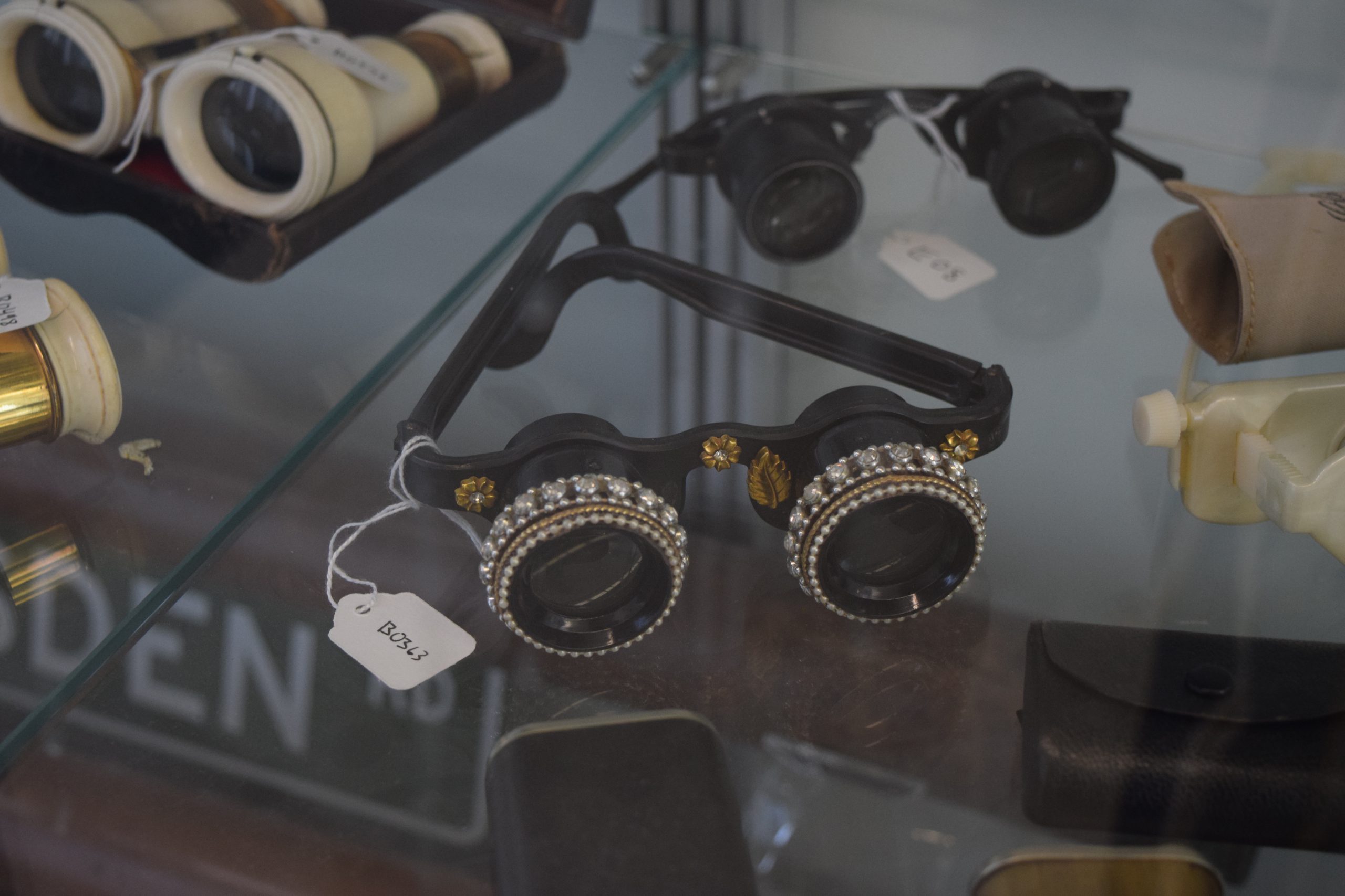 Black eye glass with gold border and rings of pearls around lenses and gold embellishments on brackets.